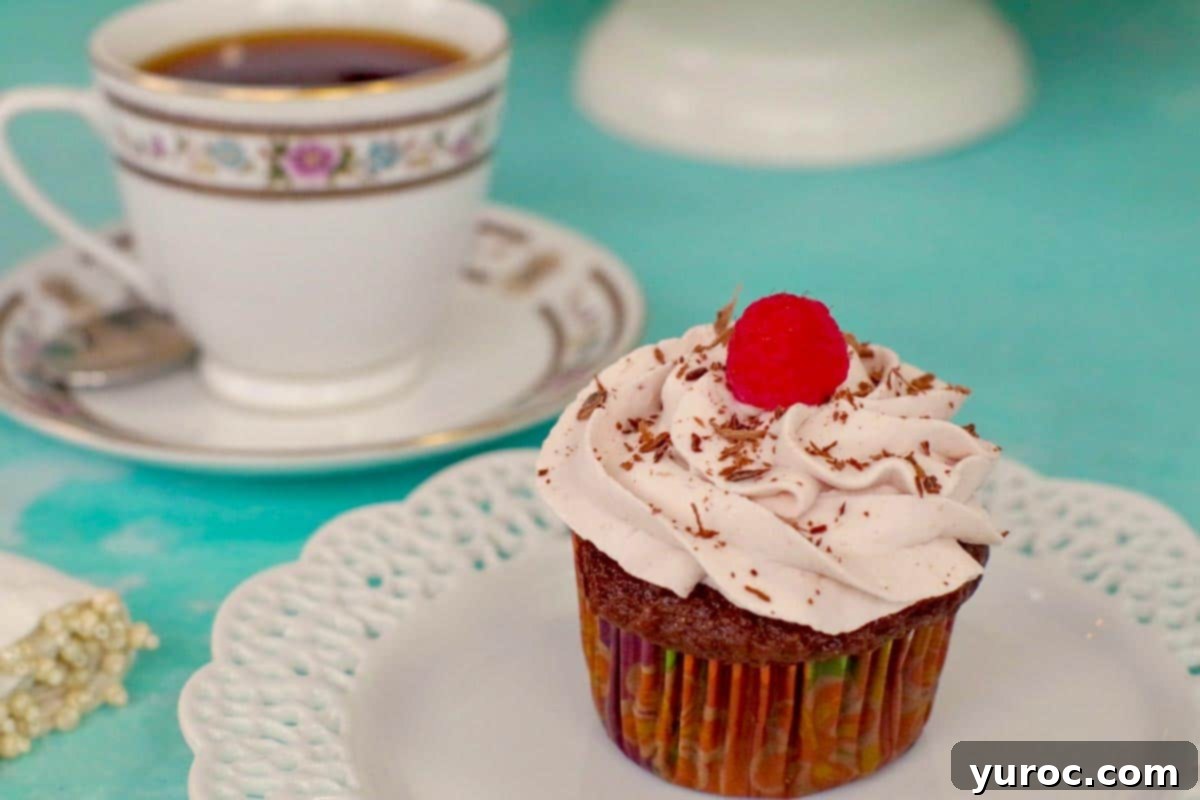 tiramisu cupcake on a white plate, with a cup of tea (in a china cup) in the background