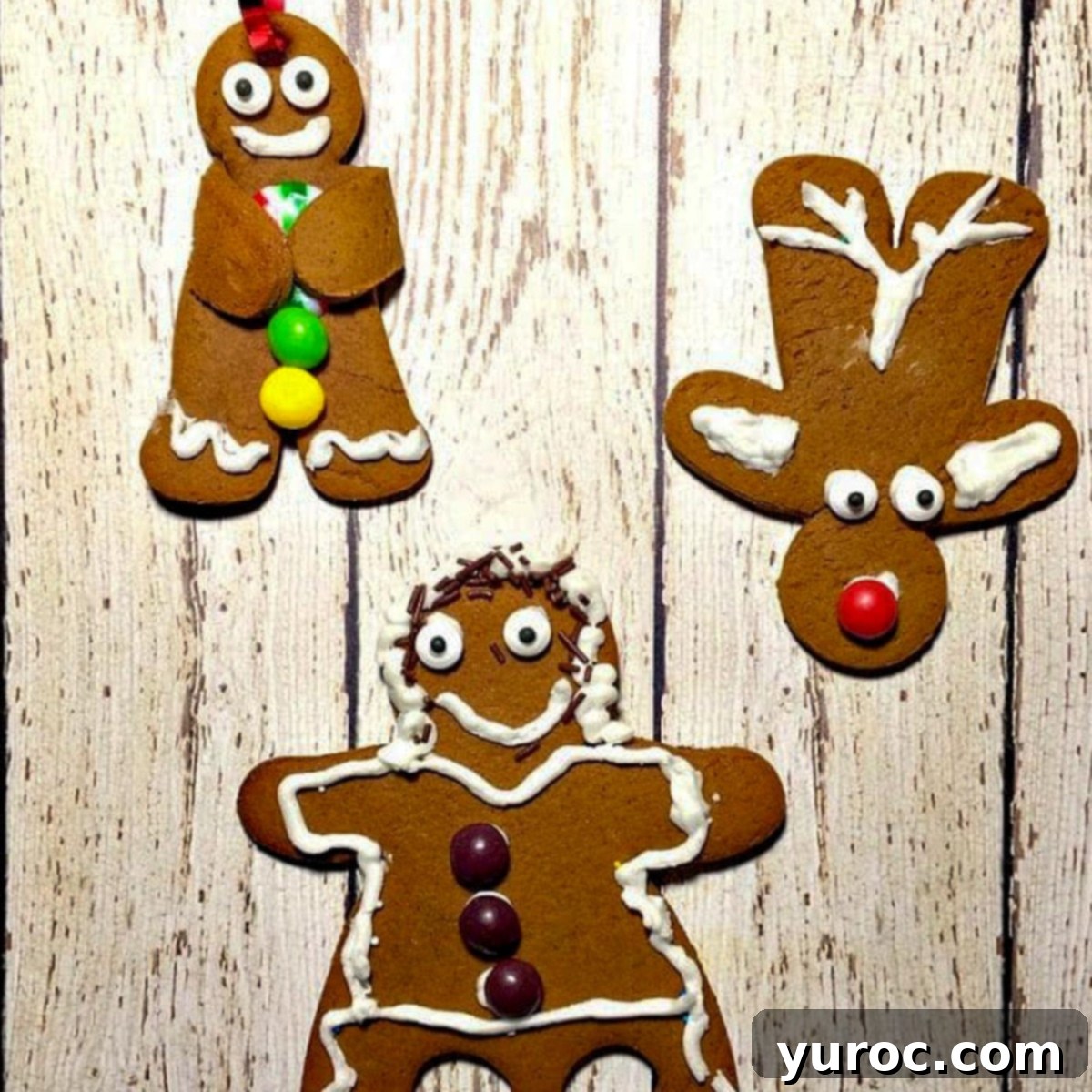 3 gingerbread cookies (a reindeer, dancing gingerbread girl and a gingerbread man) on a white faux wooden surface