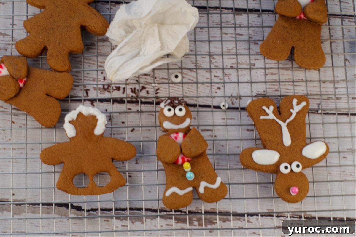 Gingerbread girl with hair and mistake on face wiped off, beside hugging gingerbread man and gingerbread reindeer.