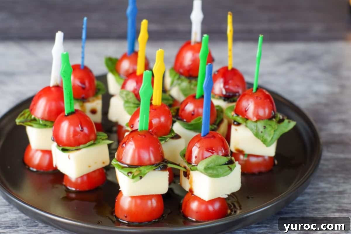 several caprese salad on a skewers on a black round tray