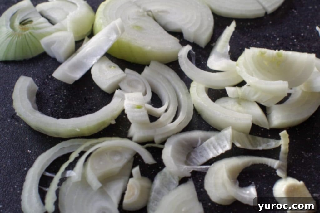 onions on black cutting board, cut in circles, then in half