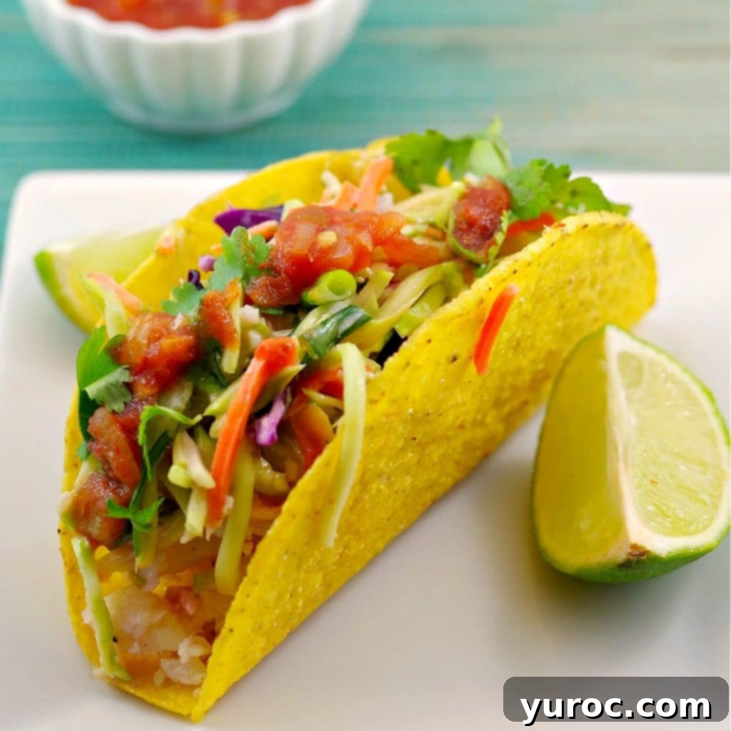 healthy fish taco on a white plate with a wedge of lemon