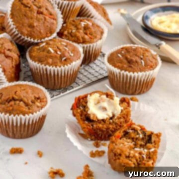15 Deliciously Healthy Bran Muffin Recipes 11 A delightful Morning Glory Bran Muffin, elegantly split in half to showcase its textured interior, presented on a white plate, with a rustic pile of more wholesome muffins visible in the background on a wire rack, evoking homemade goodness and rich flavor.