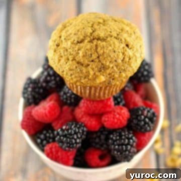 15 Deliciously Healthy Bran Muffin Recipes 2 A golden-brown Wheat Bran Muffin, with visible walnuts, elegantly presented on a plate, accompanied by a vibrant bowl of fresh mixed berries and scattered walnuts, enhancing the appetizing visual.