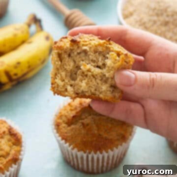 15 Deliciously Healthy Bran Muffin Recipes 7 A delicious oat bran muffin, carefully broken in half to reveal its moist, wholesome interior, held above a full muffin with ripe bananas blurred in the background, subtly suggesting natural sweetness.