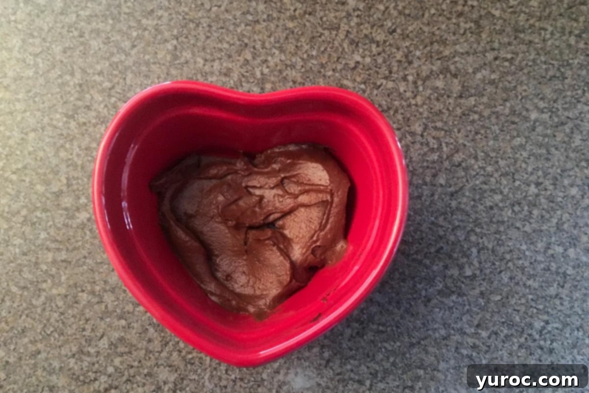 Layers of avocado mousse and graham crackers in a red heart-shaped dish