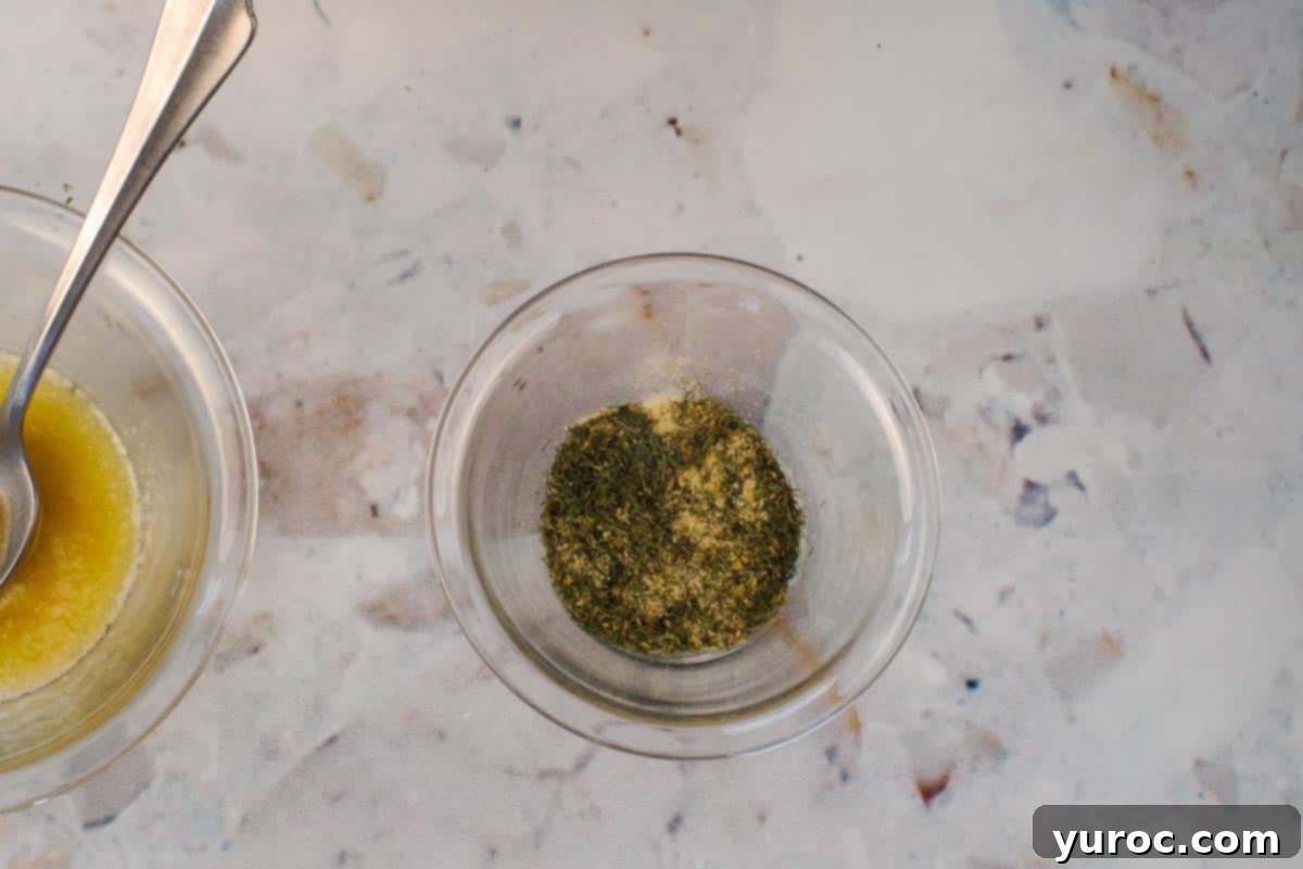 Dill, garlic powder, onion powder and lemon pepper mixed together in small glass bowl.
