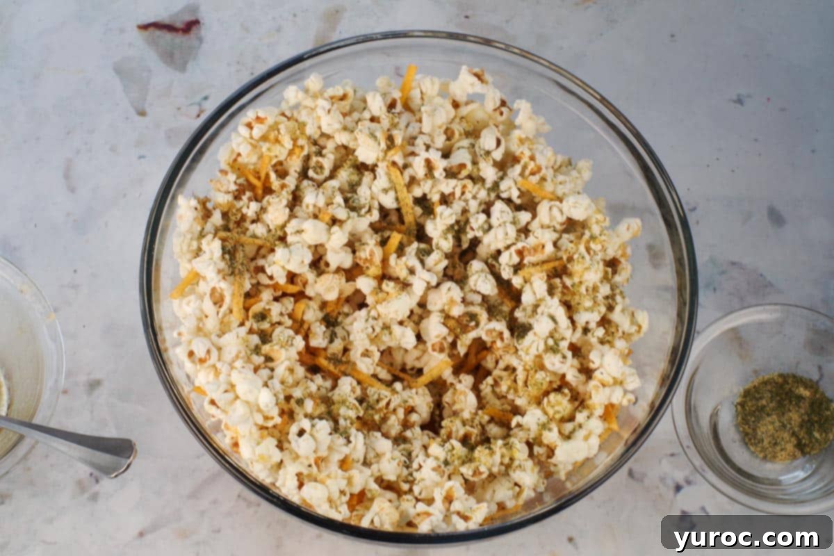 Popcorn in a large glass bowl with half the butter mixture and half the spice mixture poured on.