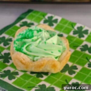 A festive St. Patrick's Day dessert Shamrock Tart on a green shamrock patterned napkin, showcasing its vibrant green filling and delicate crust.