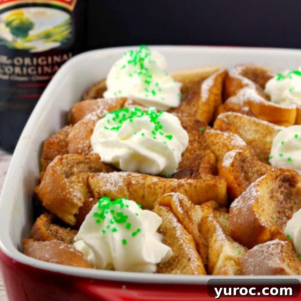 A delicious Baileys French Toast Casserole presented in a white and orange baking dish, with a bottle of Baileys Irish Cream gracefully positioned in the background, ideal for a festive breakfast.
