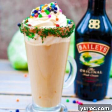 A refreshing Mint Irish Latte elegantly placed on a wooden surface, with a bottle of Baileys subtly featured in the background, making it a perfect St. Patrick's Day coffee.