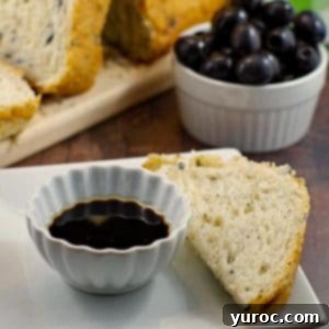 Loaf of Bread Machine Onion and Olive Bread, container of black olives and oil and vinegar in a dish with piece of bread for dipping