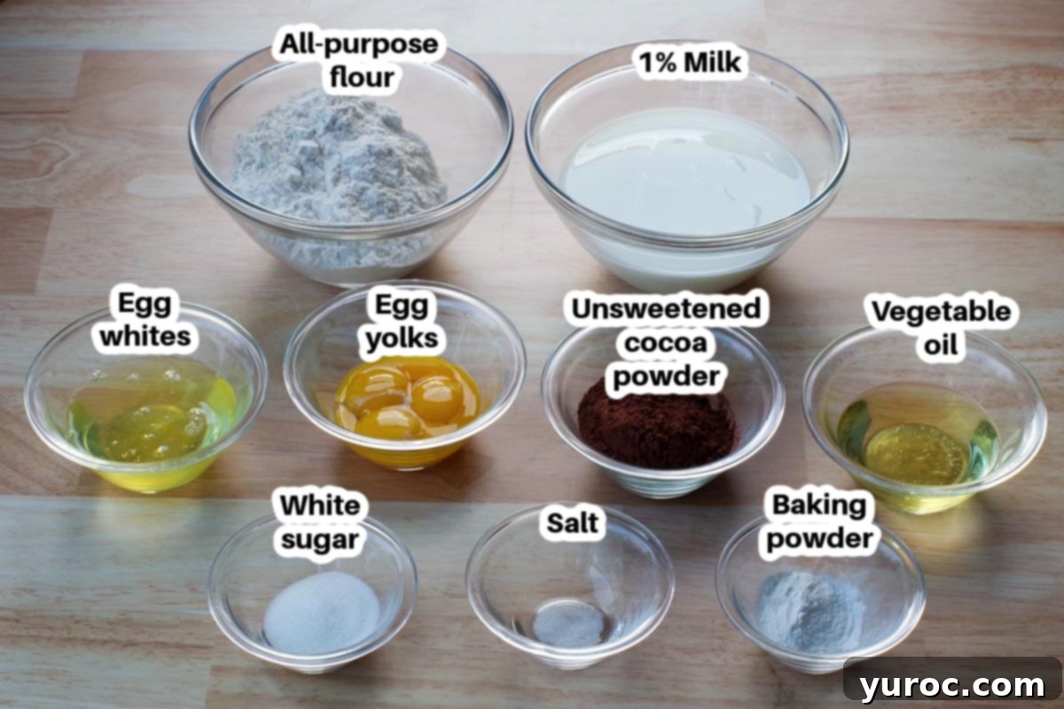 Decadent Belgian Chocolate Waffles 3 Belgian chocolate waffle ingredients in glass bowls, labelled: flour, cocoa powder, sugar, baking powder, salt, milk, vegetable oil, egg whites, egg yolks.