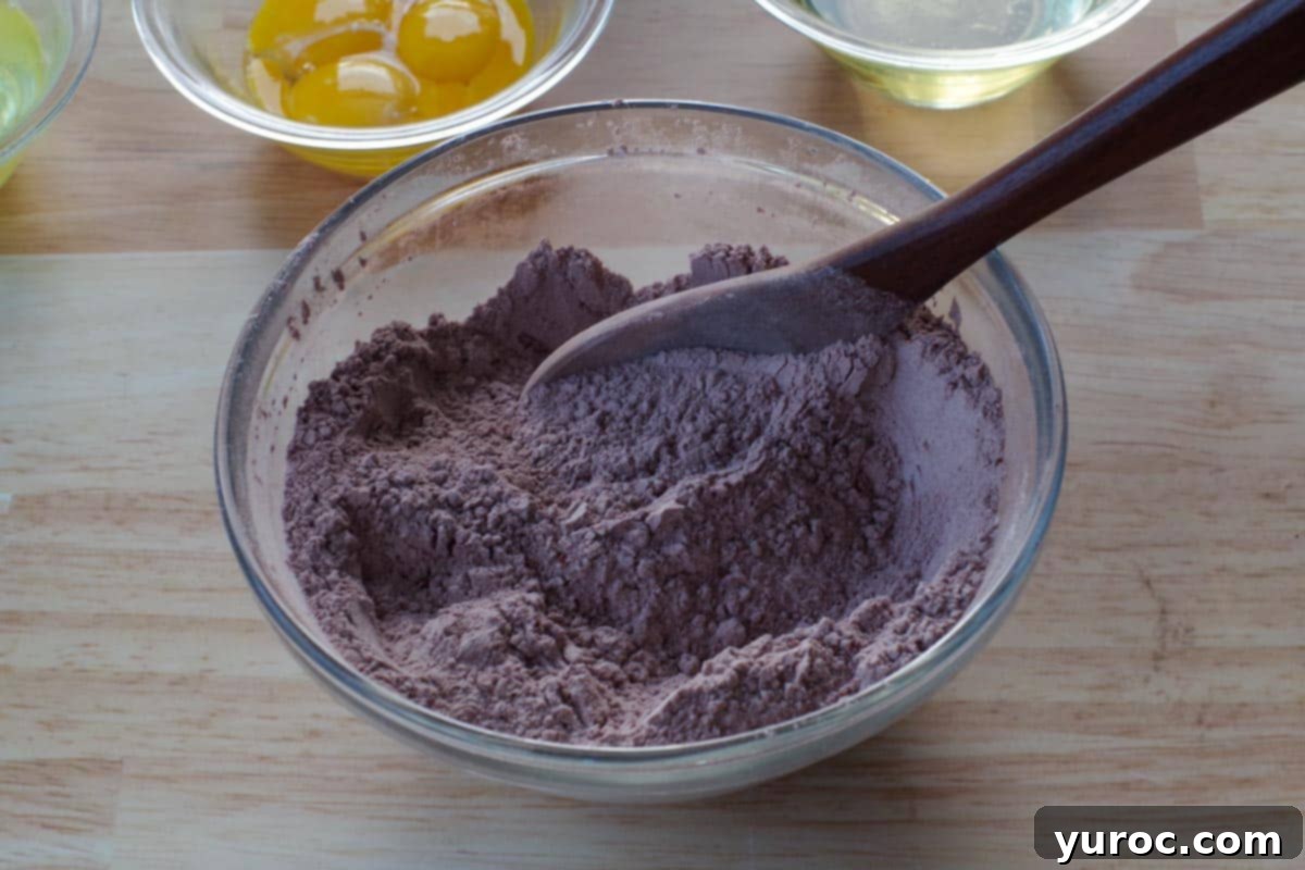 Decadent Belgian Chocolate Waffles 4 dry ingredients being stirred together in glass bowl, with wooden spoon