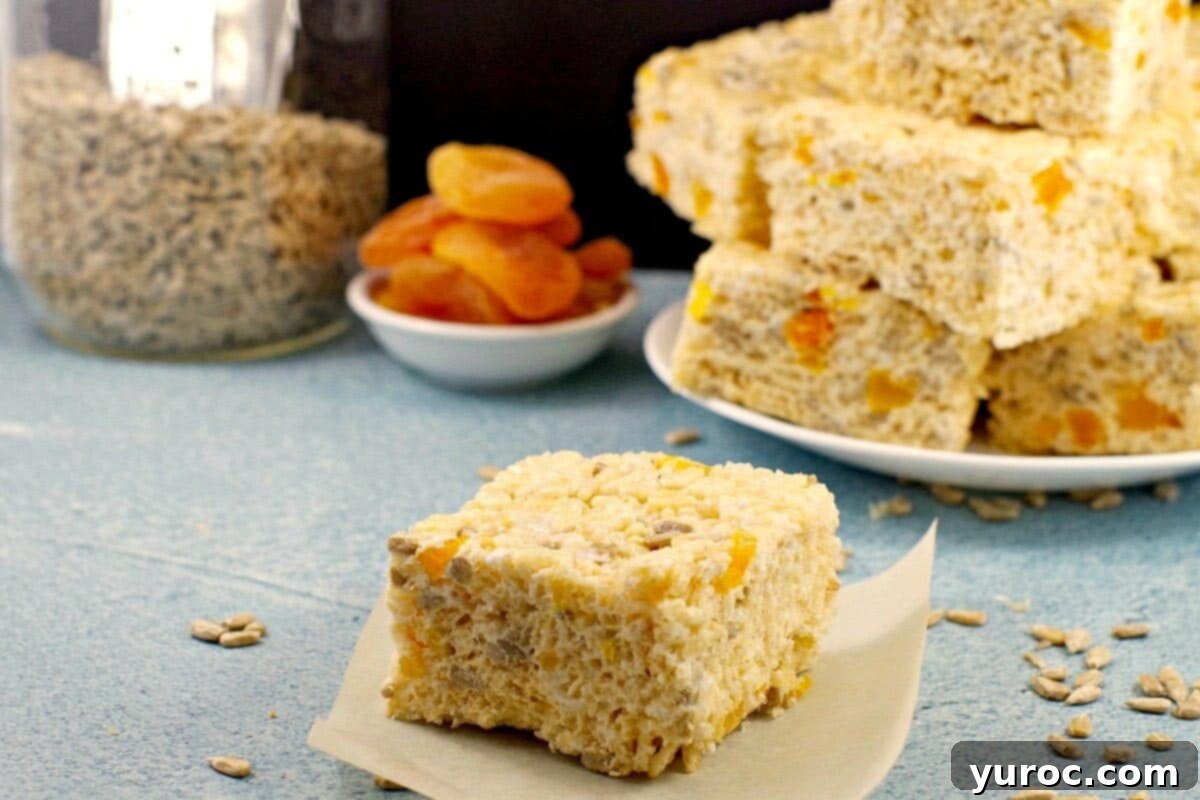 healthier rice krispie treats on a piece of parchment on blue surface with more treats in the background