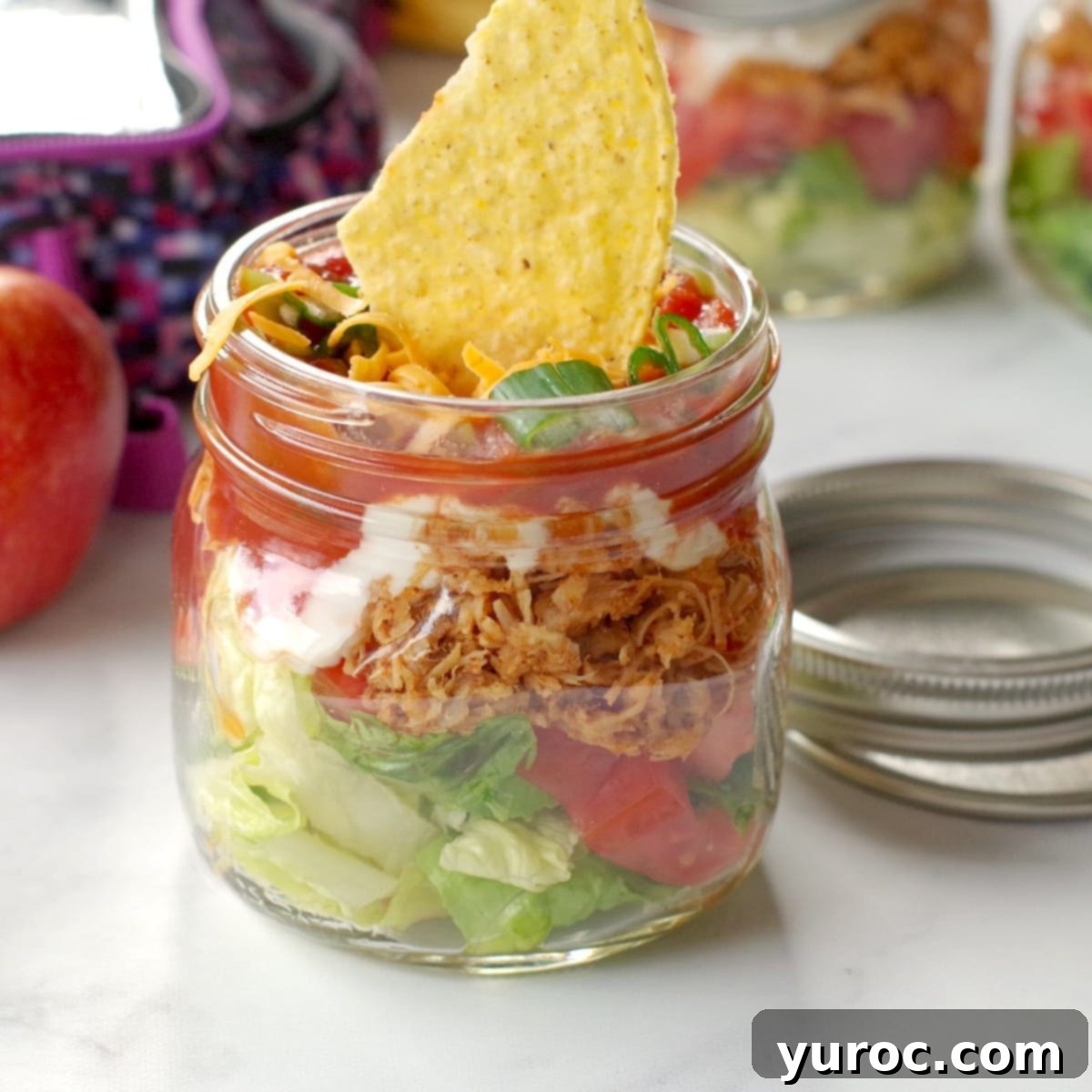 Wholesome Blueberry Cornbread Delight 15 Mason jar chicken taco salad next to more jars and a lunchbag, perfect for a healthy packed lunch.