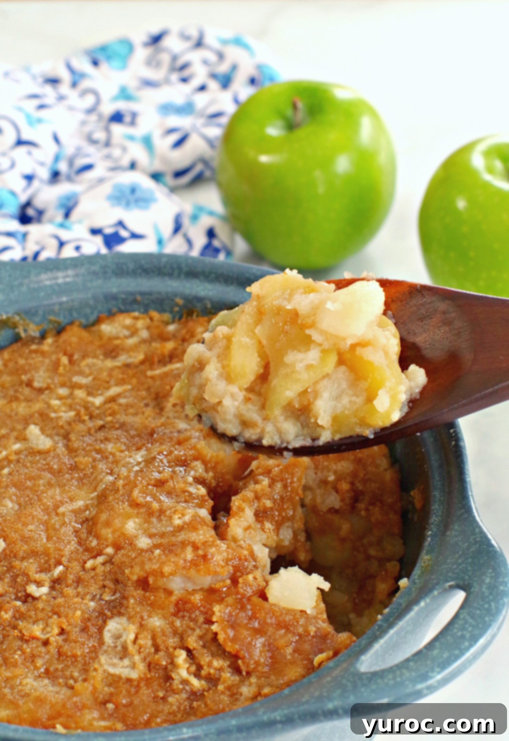 Golden Turnip Apple Bake 4 turnip and apple casserole (weight watchers friendly in a blue casserole dish, being held up on a wooden spoon with a green apple and blue patterned oven mitt in the background