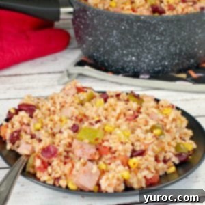 leftover ham, rice and beans on a black plate with fork and speckled pot in the background