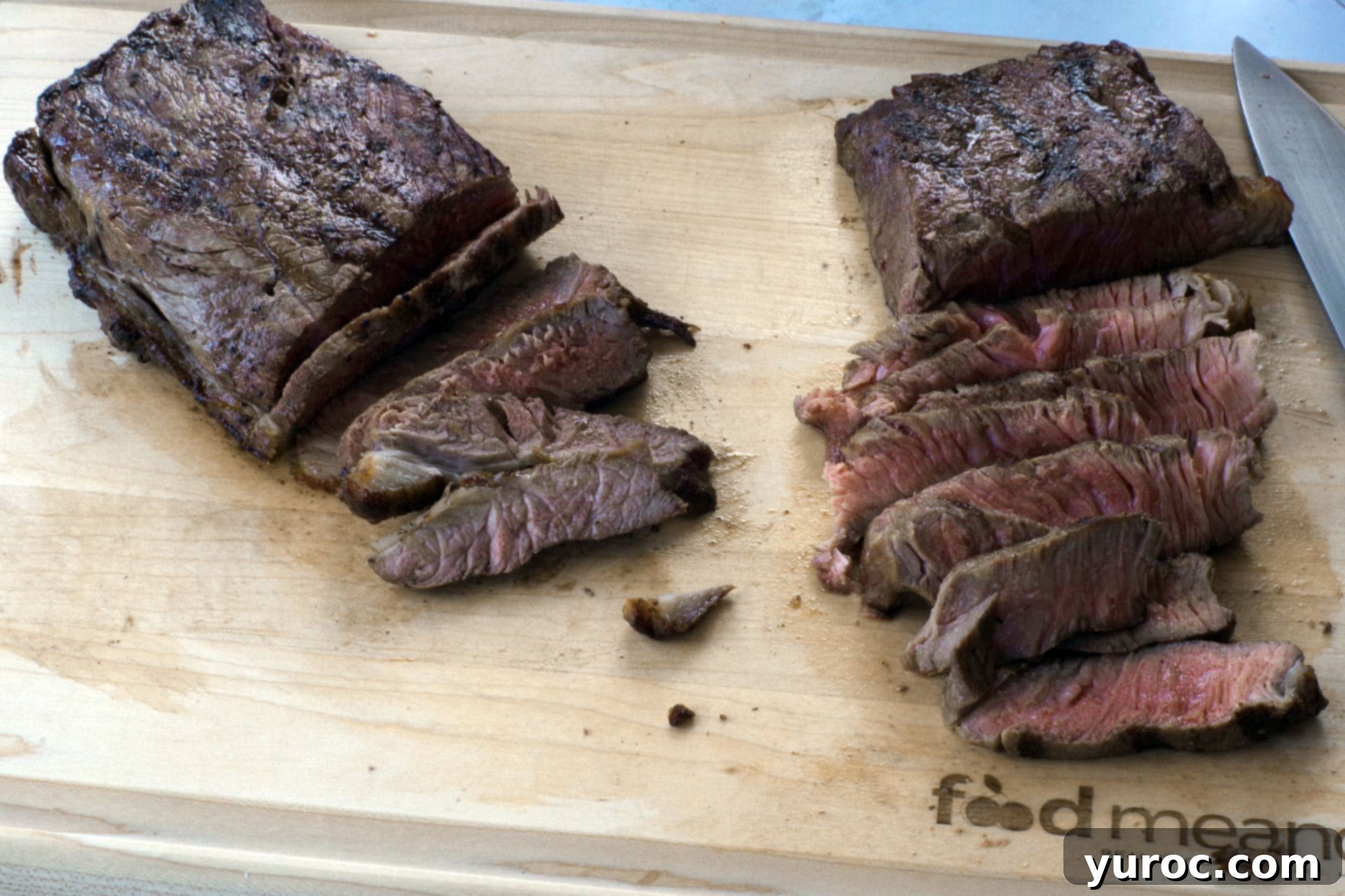 Grilled steak being sliced into thin strips on a wooden cutting board.