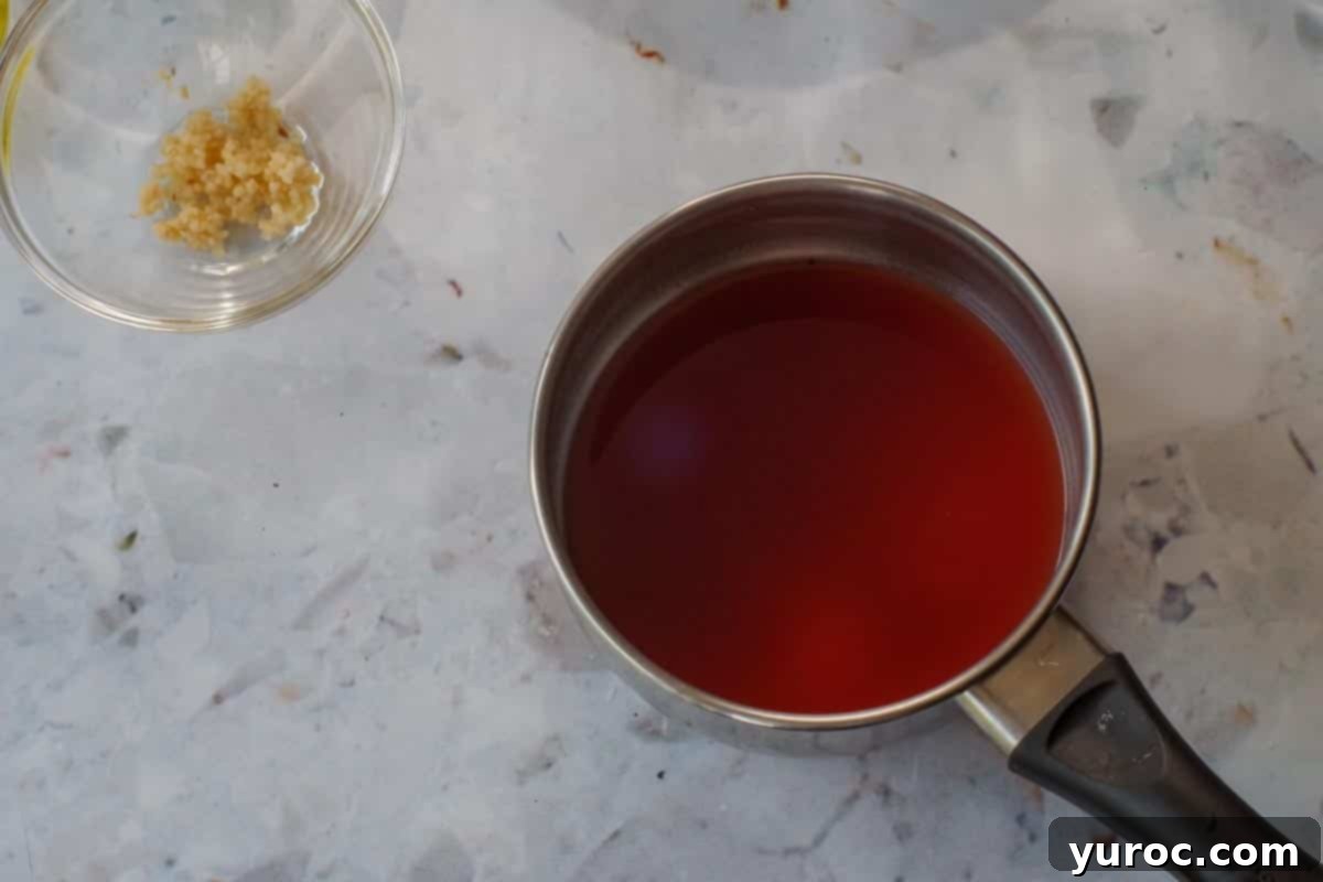 Clamato juice being heated in a small saucepan on a stovetop.