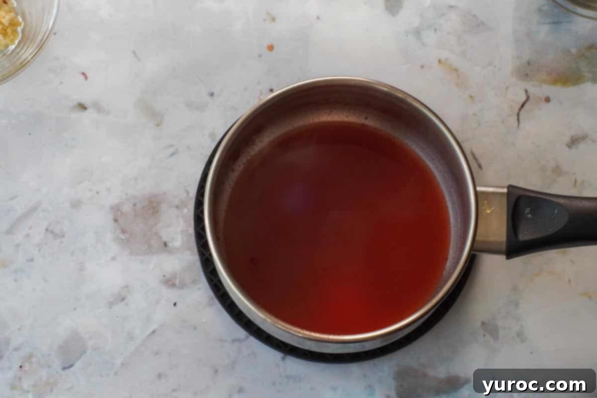 Reduced Clamato juice simmering in a small saucepan, thickened.