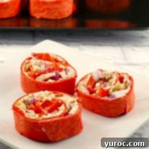 Chicken Tortilla Swirls 5 chicken tortilla pinwheels on a white plate with a tray of pinwheels in the background