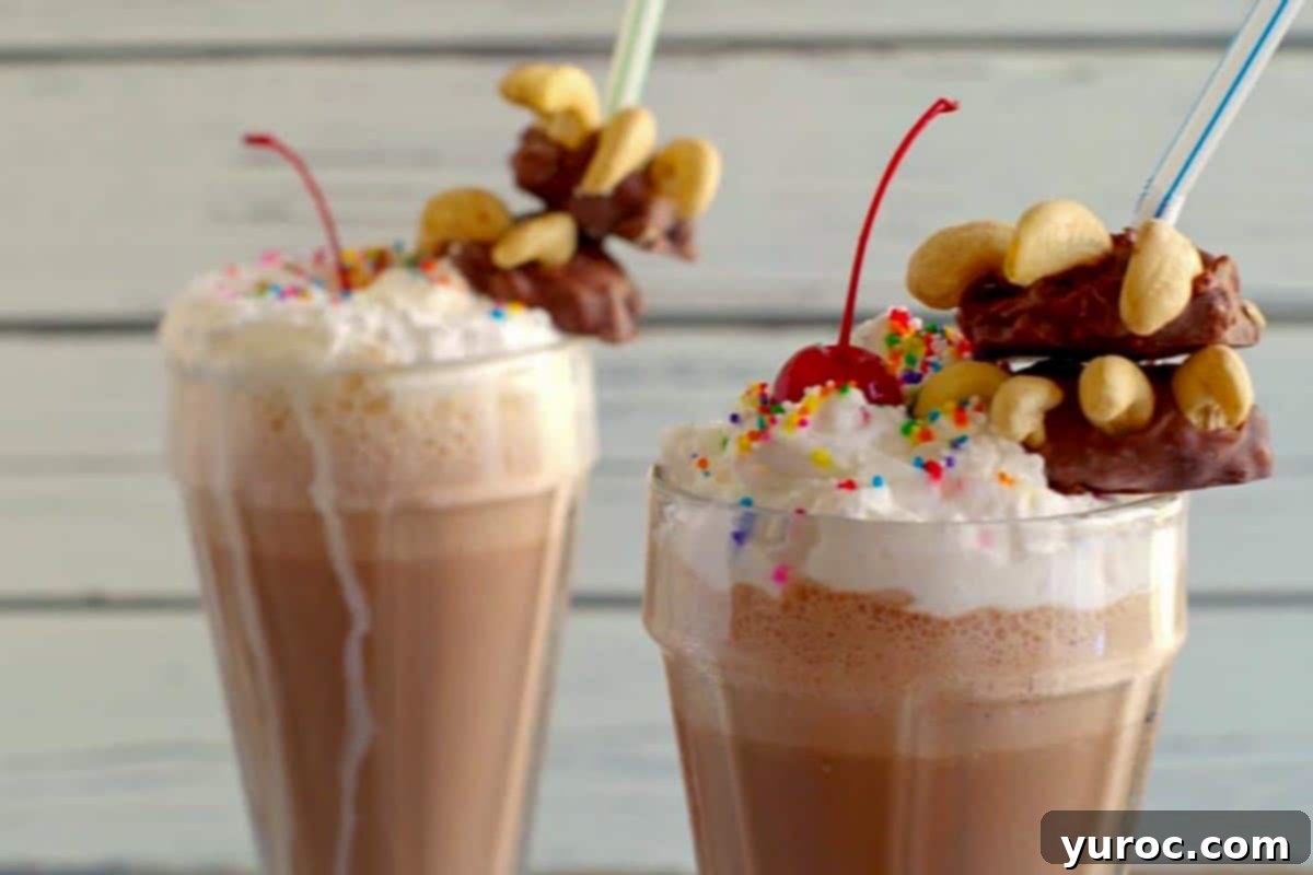 Close-up of a Bear Claw fancy milkshake, featuring a chocolate garnish and whipped cream, with another milkshake in the soft background.