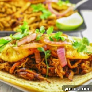 pineapple carnita on a soft taco shell with a tray of carnitas in background