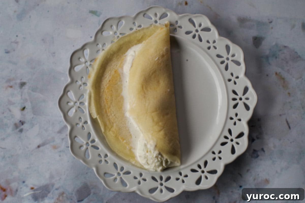 One side of the crepe folded lengthwise over the ice cream.