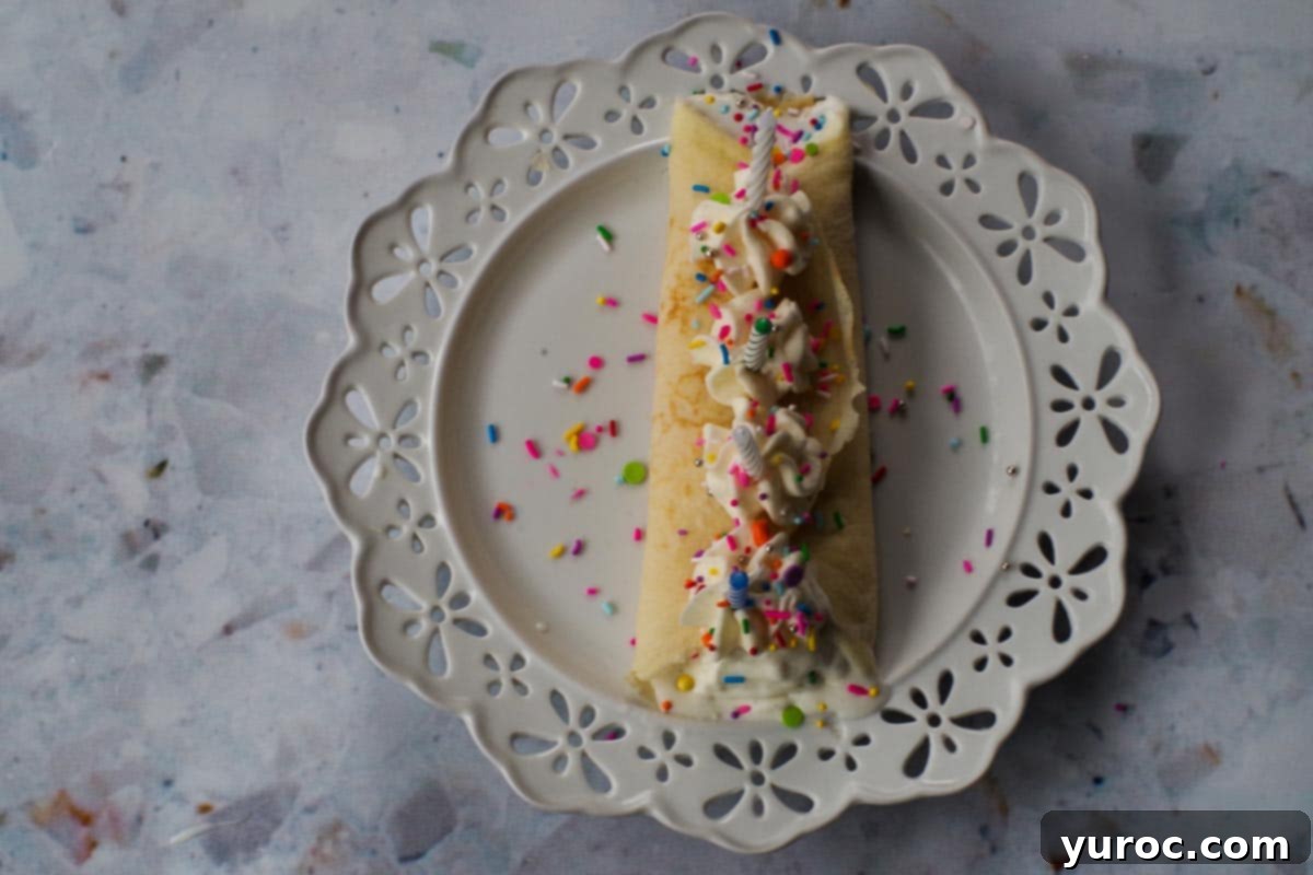 Decorated crepe with piped buttercream, sprinkles, and birthday candles.