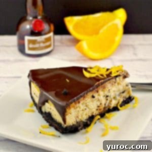 grand marnier cheesecake on white plate with slices of orange and mini bottle of grand marnier in the background