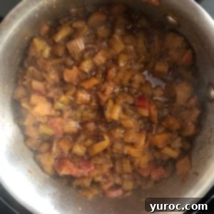 Rhubarb compote gently simmering in a saucepan on the stovetop, releasing its aromatic steam.