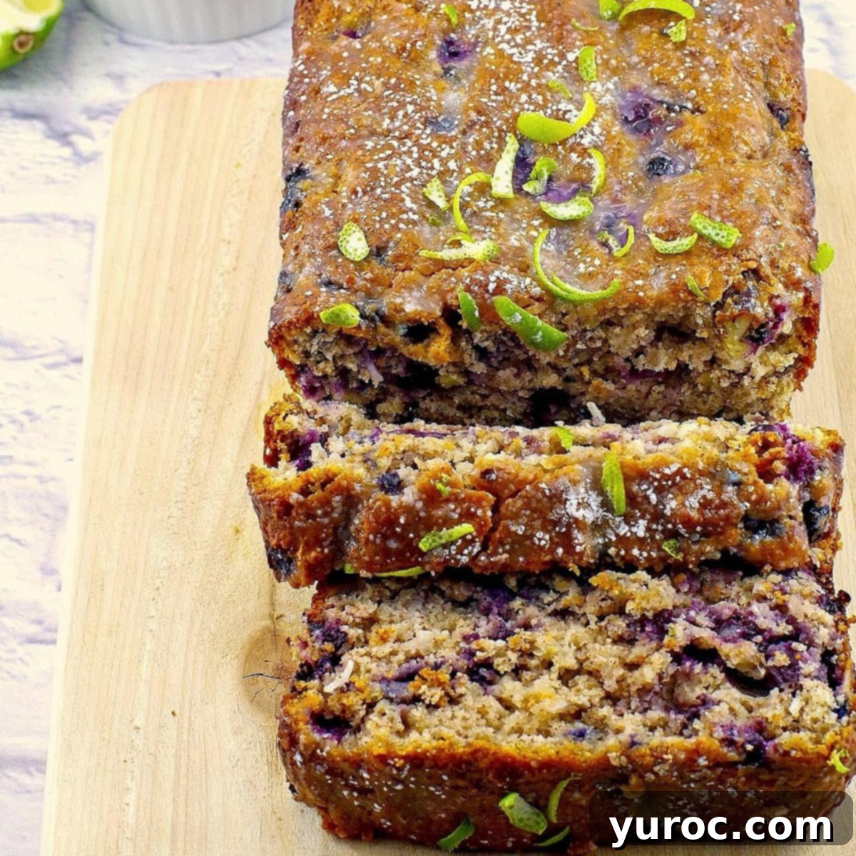 A delicious gingerbread loaf on a cutting board, surrounded by fresh blueberries and limes, highlighting the key flavors of ginger and citrus.
