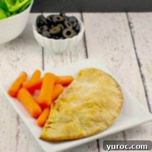 Wholesome Pita Pizza Pouches 14 A healthy pizza pocket on a white plate with baby carrots and a dish of olives and spinach in the background, ready to be enjoyed.