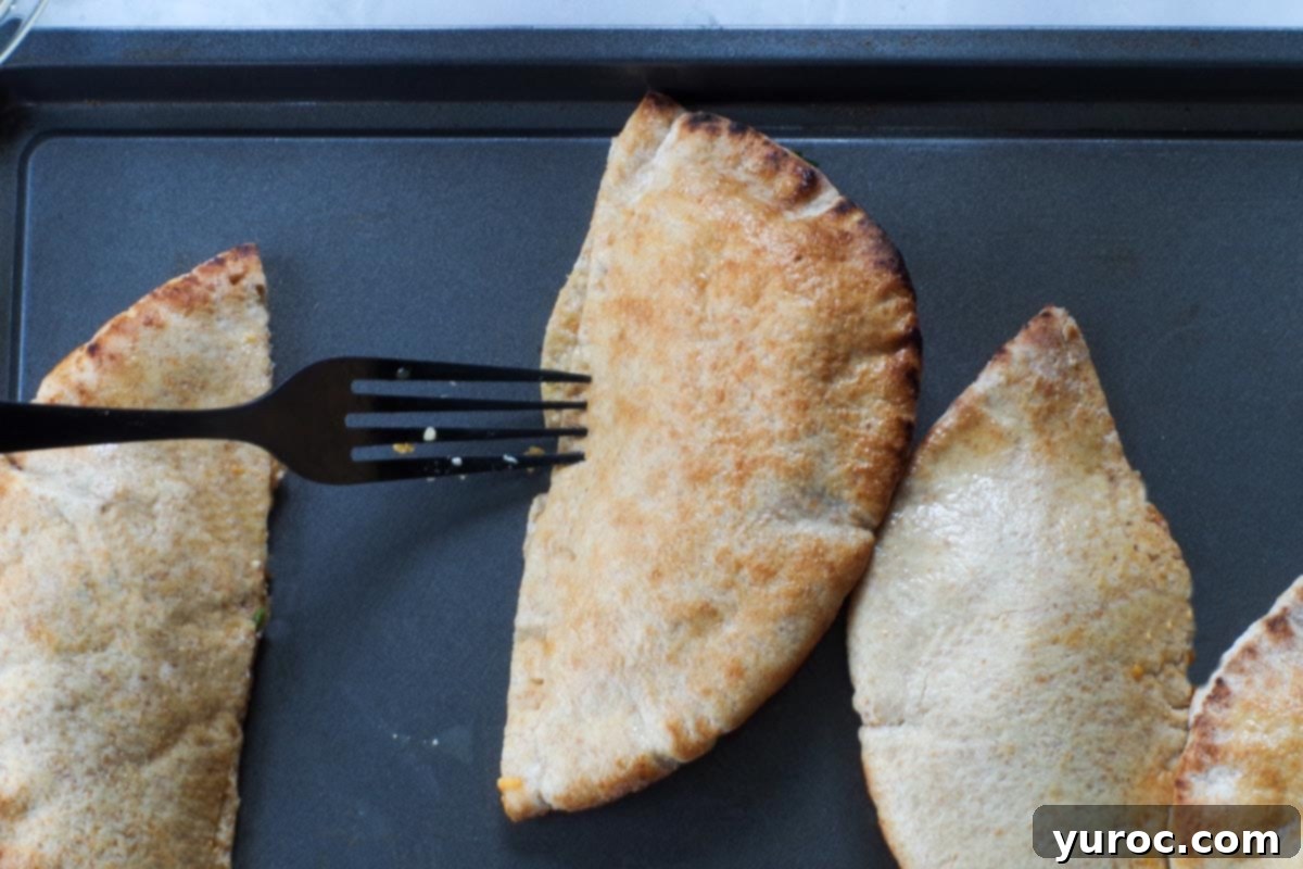 Wholesome Pita Pizza Pouches 10 Pita being sealed with a fork on a baking sheet, creating a crimped edge.
