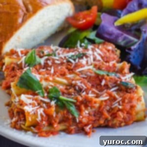 baked beef cannelloni on a white plate with salad and garlic toast