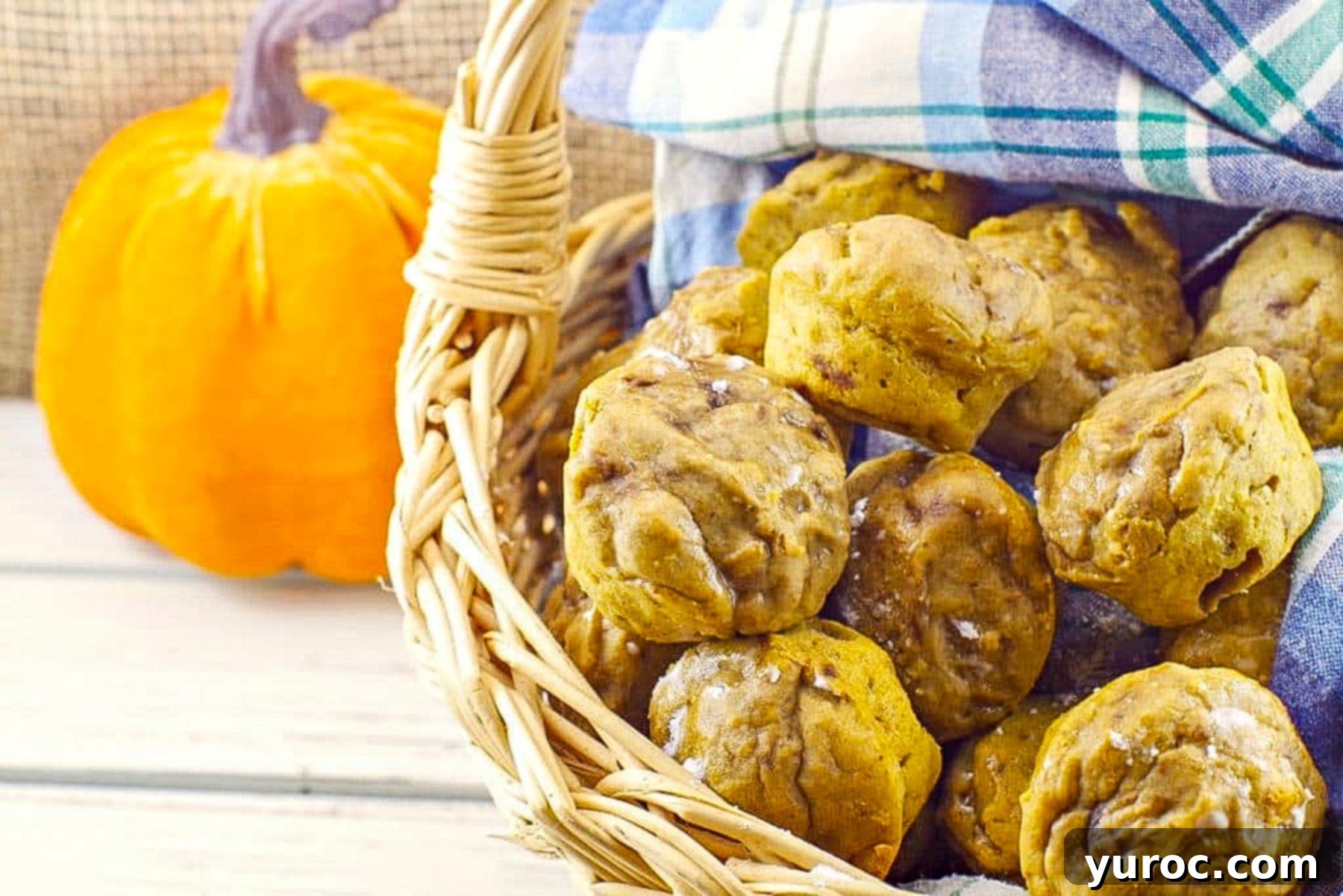 Weight Watchers mini pumpkin muffins in a basket with a blue checkered cloth and a pumpkin prop in the background
