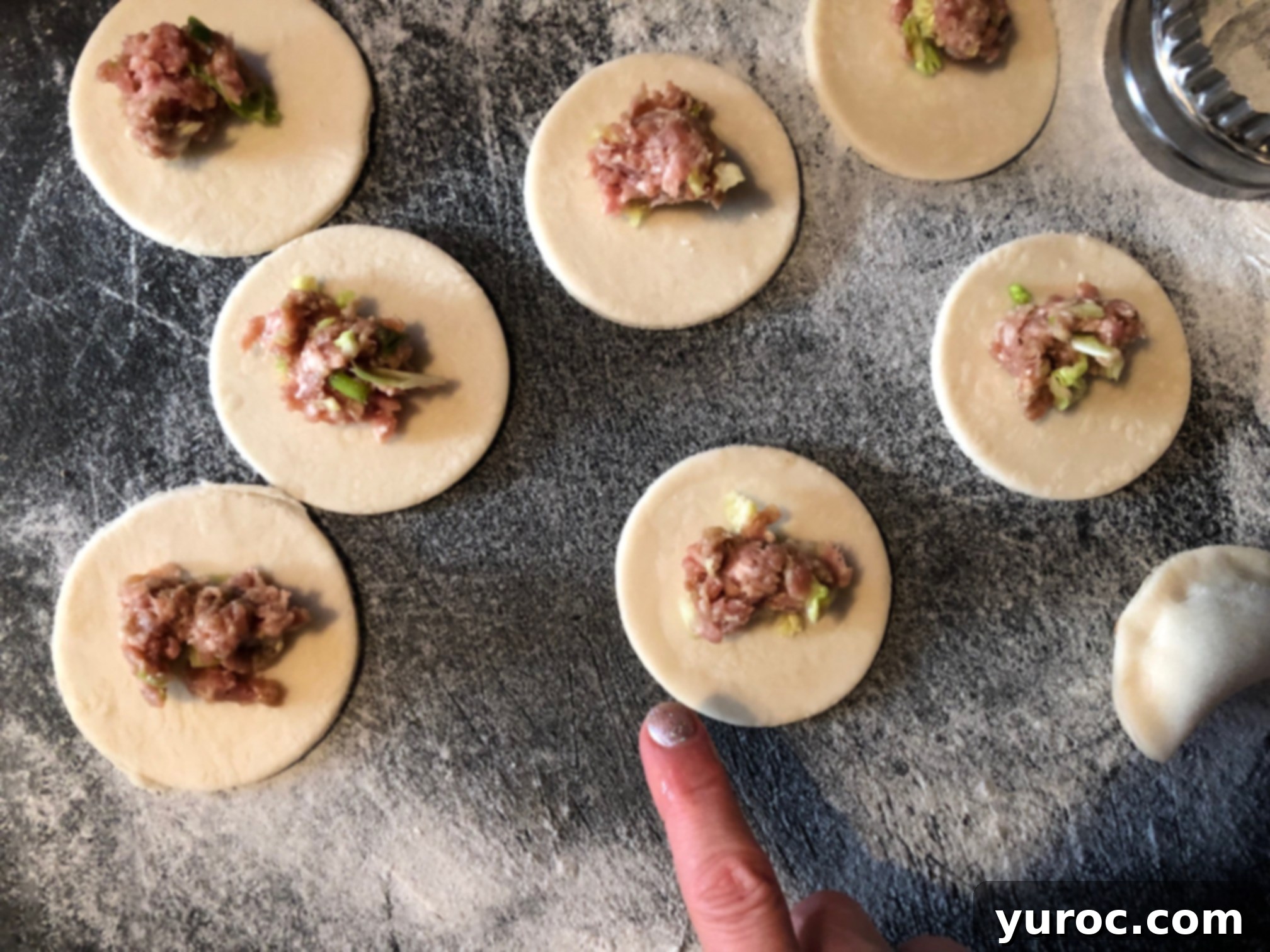 Moistening edges of Chinese potsticker dough circles for sealing