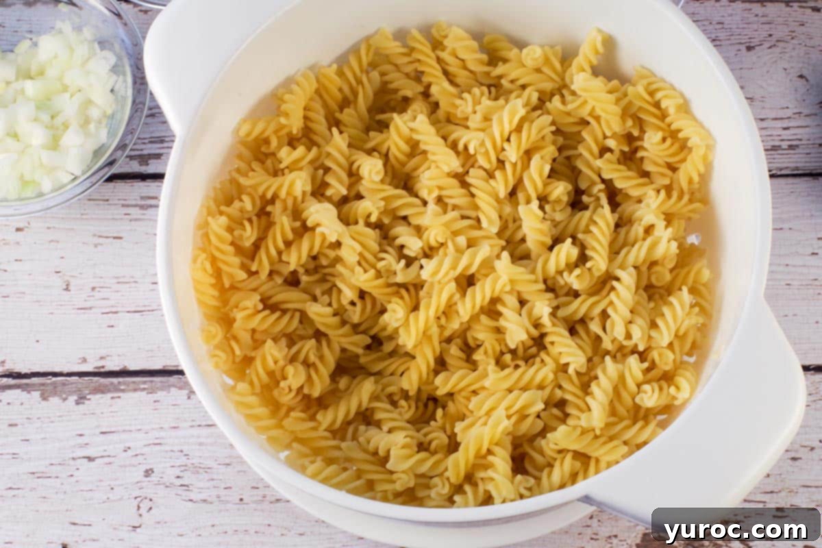 Drained pasta in colander on faux wood surface.