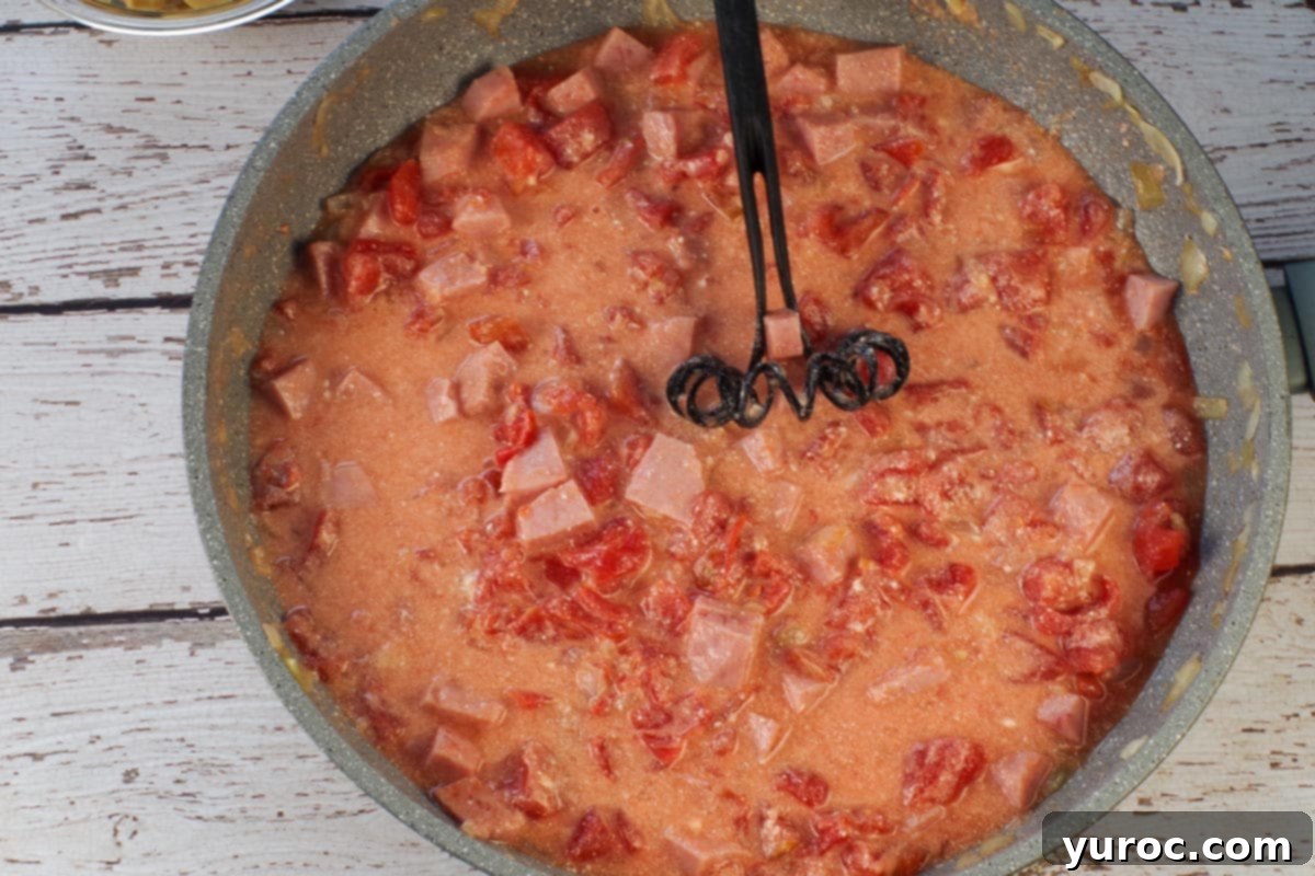 Mascarpone cheese whisked into ham mixture in large skillet with black whisk