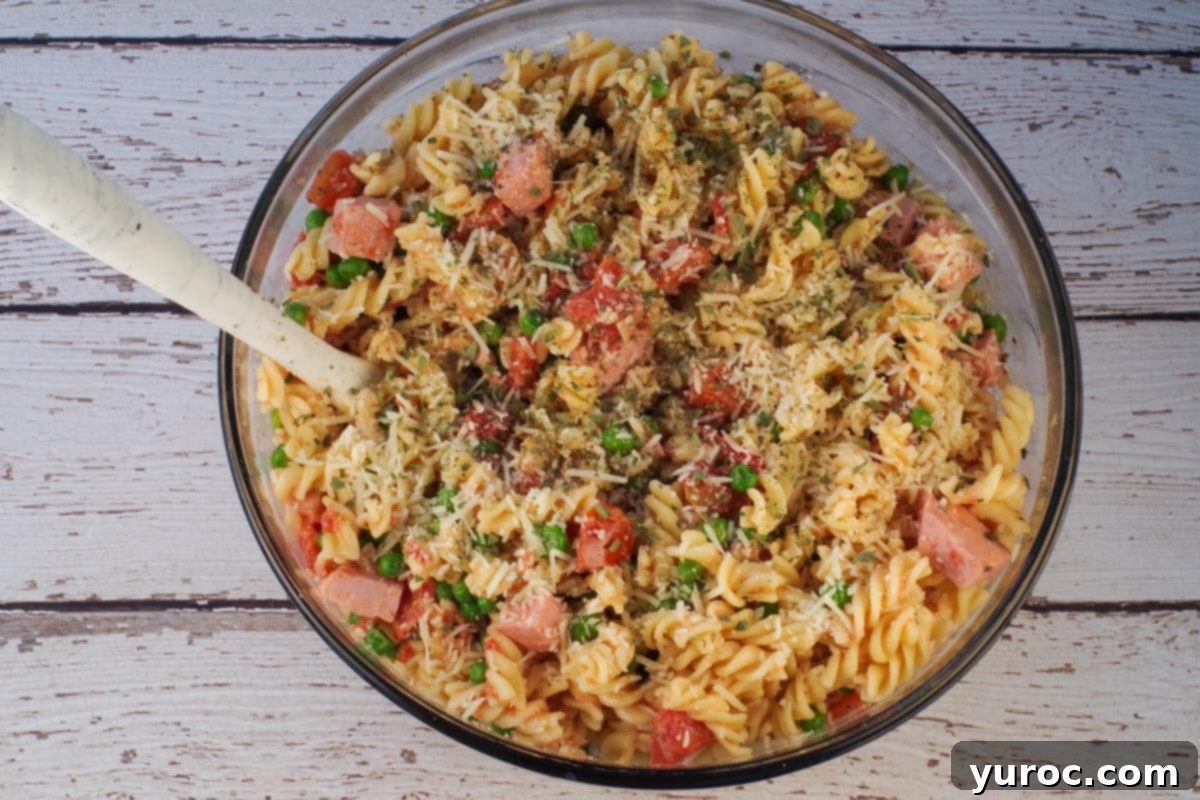 Pasta added to ham mixture in large glass bowl.