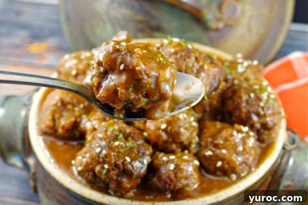 Sticky Sweet and Sour Slow Cooker Meatballs 3 Sweet and Sour Slow Cooker Meatballs in a ceramic dish with one meatball being held up with a spoon.