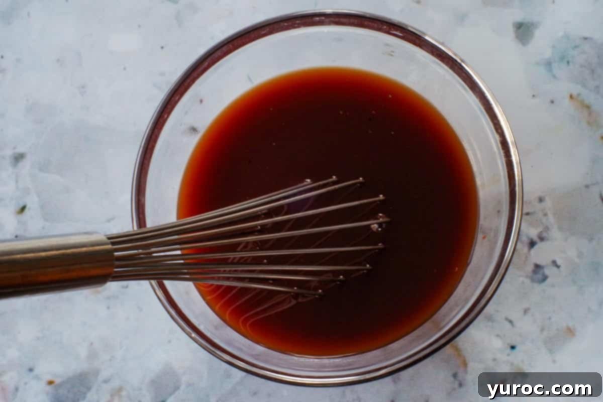 Sticky Sweet and Sour Slow Cooker Meatballs 8 Sauce ingredients whisked together in glass bowl with metal whisk.