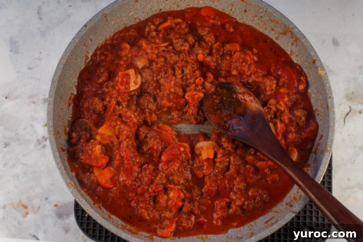 Prep-Ahead No-Boil Lasagna 5 Lasagna meat sauce simmering in a skillet, reducing slightly