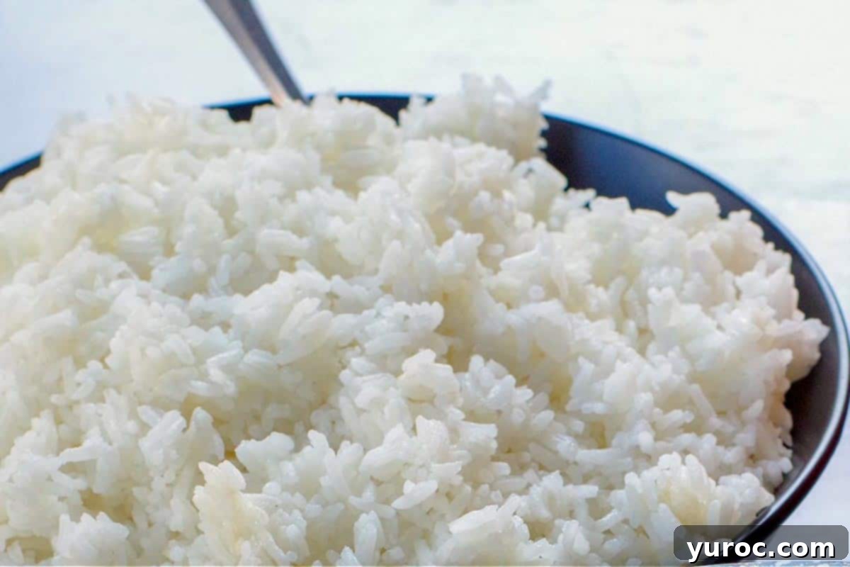 cooked Jasmine rice in a black bowl with a spoon