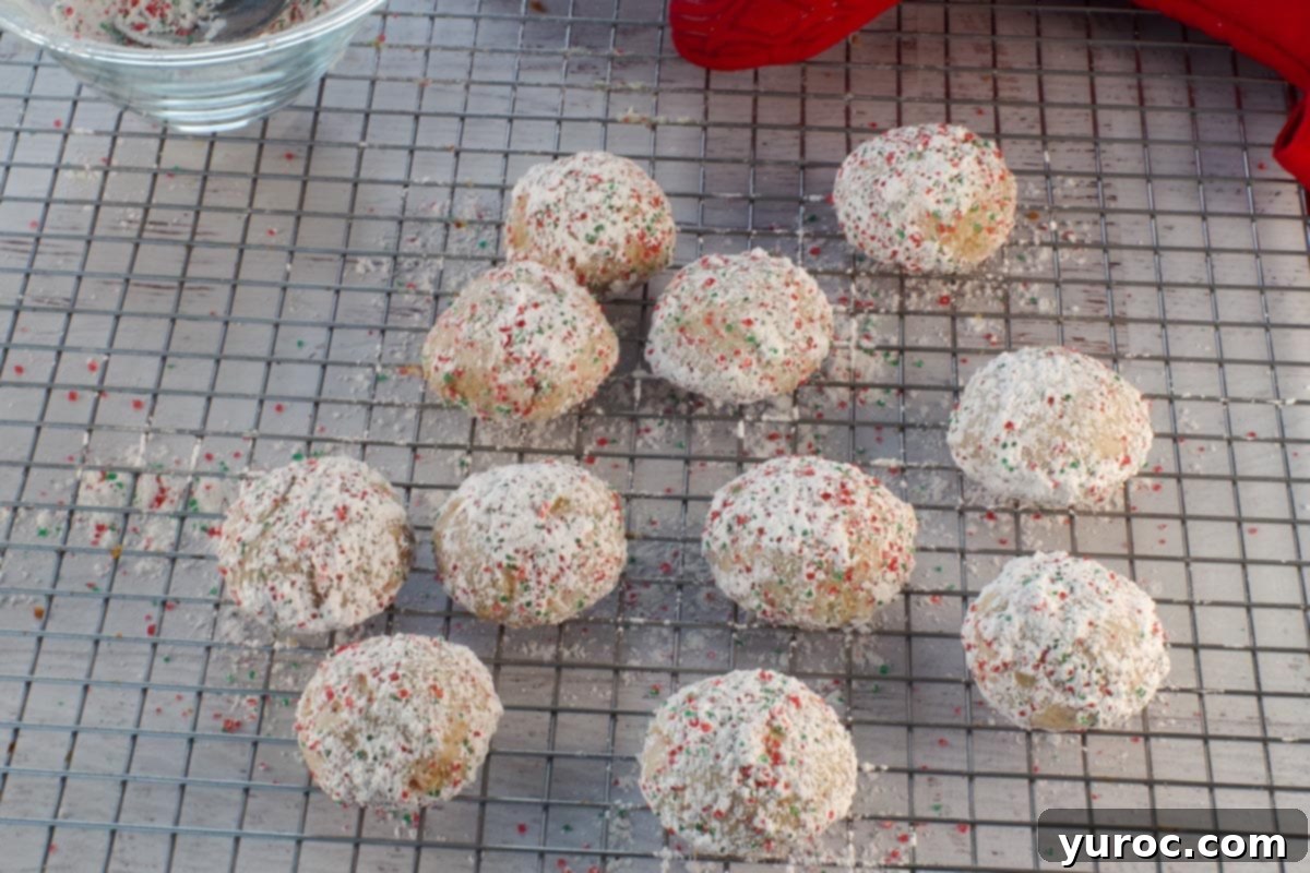 Winter Spice Almond Snow Puffs 15 Almond snowball cookies with powdered sugar on a wire rack, cooling.