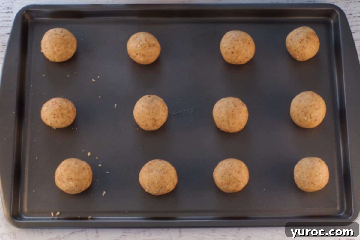 Winter Spice Almond Snow Puffs 8 Almond Snowball Cookies placed on a cookie sheet, ready for baking.