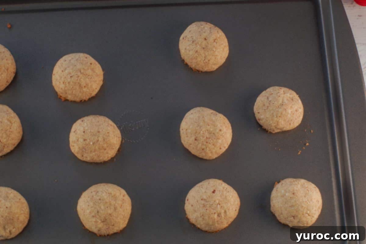 Winter Spice Almond Snow Puffs 9 Baked Almond Snowball Cookies on a cookie sheet, golden brown on the bottom.