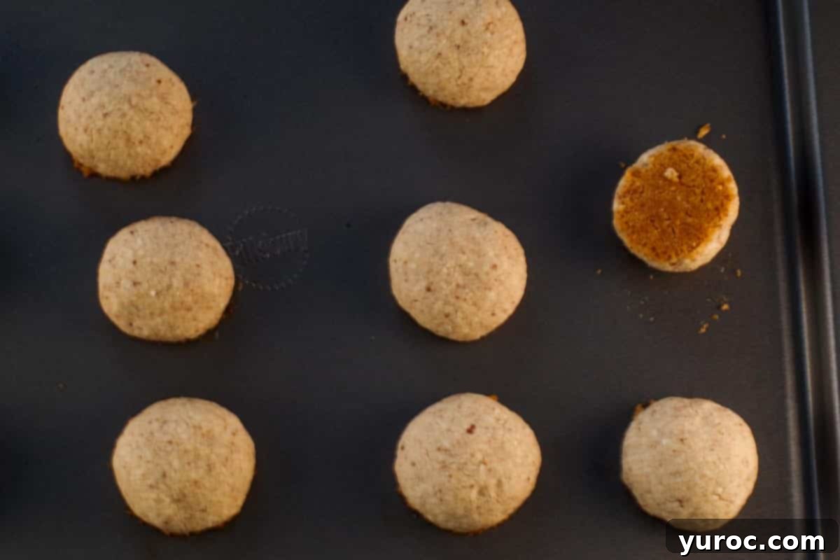 Winter Spice Almond Snow Puffs 10 Close-up of the browned bottom of a snowball cookie on a cookie sheet.