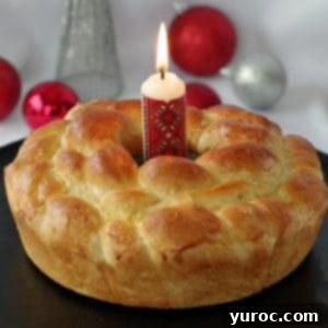 Kolach Ukrainian Christmas Bread on black platter with Ukrainian candle in the middle and Christmas decorations in the background